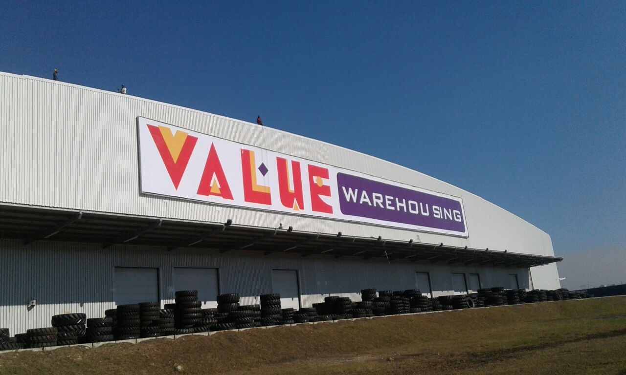 Large printed Value Warehousing building signage mounted on a warehouse facade